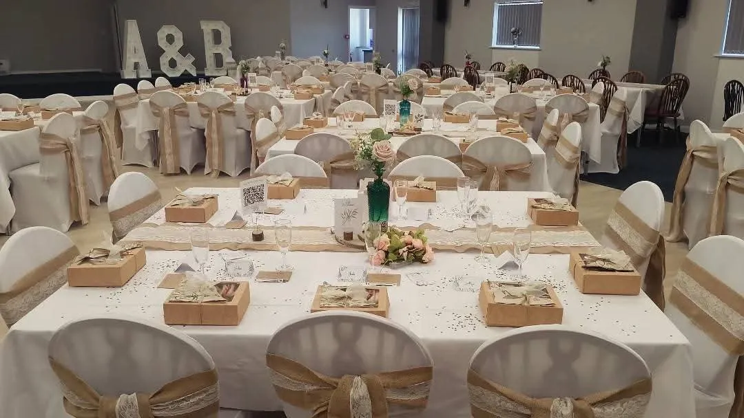 A wedding reception room with kraft picnic boxes laid on every place setting